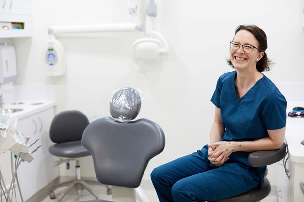 Dentist wearing blue shirt and glasses smiling in dental clinic near Claremont